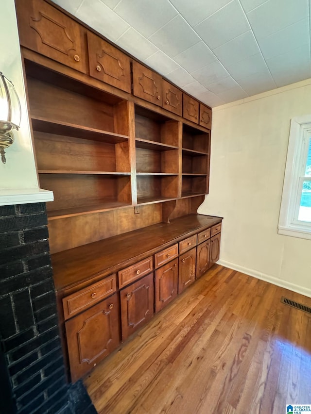 unfurnished office featuring built in shelves and light hardwood / wood-style floors