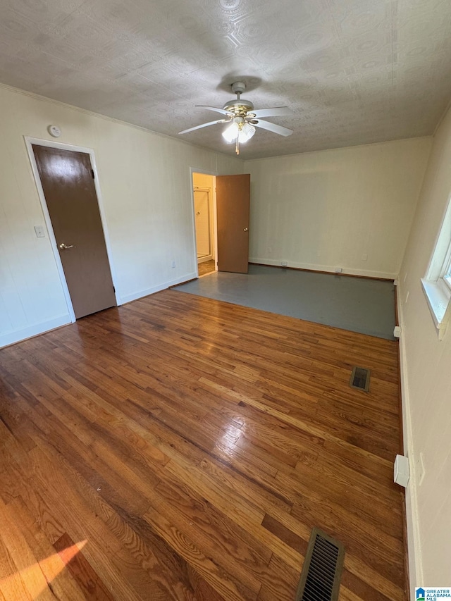 empty room with a textured ceiling, hardwood / wood-style flooring, and ceiling fan