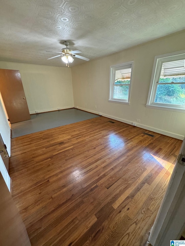 unfurnished room featuring a textured ceiling, a wealth of natural light, and dark wood-type flooring