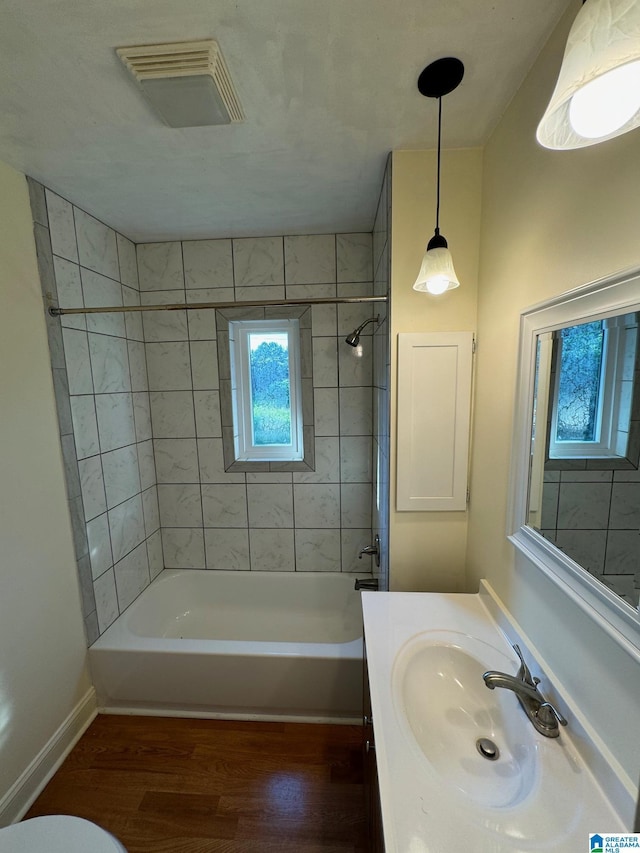 full bathroom with hardwood / wood-style floors, vanity, toilet, and tiled shower / bath