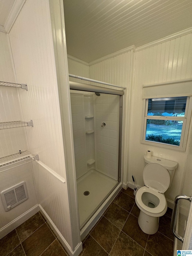 bathroom with tile patterned flooring, wood walls, toilet, a shower with door, and ornamental molding