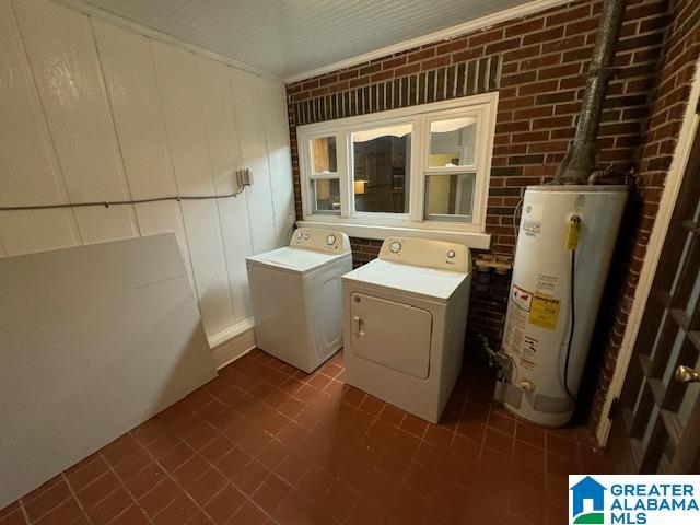 washroom featuring washer and dryer, gas water heater, and brick wall