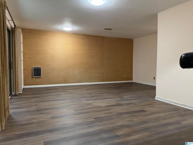 empty room with dark hardwood / wood-style flooring and heating unit