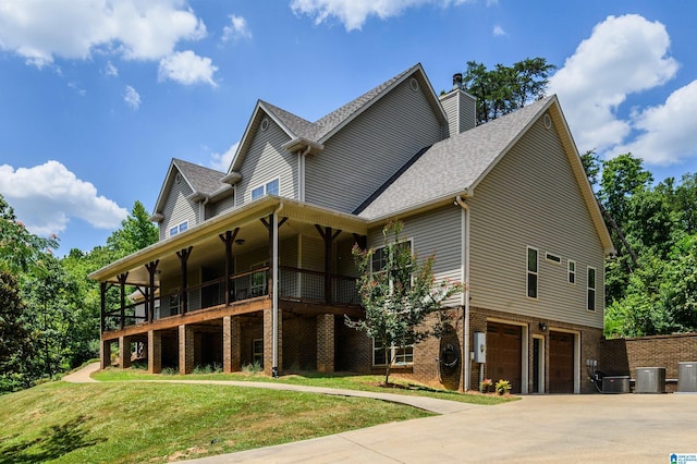 view of front of property featuring a garage, a front lawn, central air condition unit, and a balcony