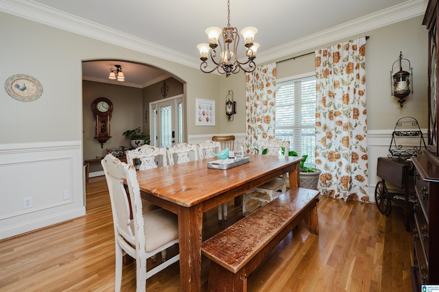 dining space featuring crown molding, an inviting chandelier, and light hardwood / wood-style flooring