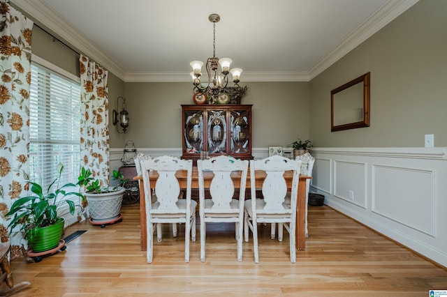 dining area with crown molding, a notable chandelier, and light hardwood / wood-style floors