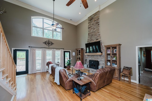 living room with crown molding, ceiling fan, light hardwood / wood-style floors, and a high ceiling