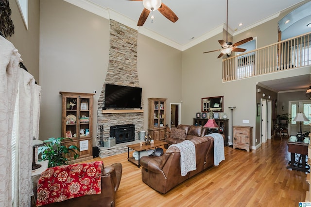 living room with crown molding, a towering ceiling, and light hardwood / wood-style flooring