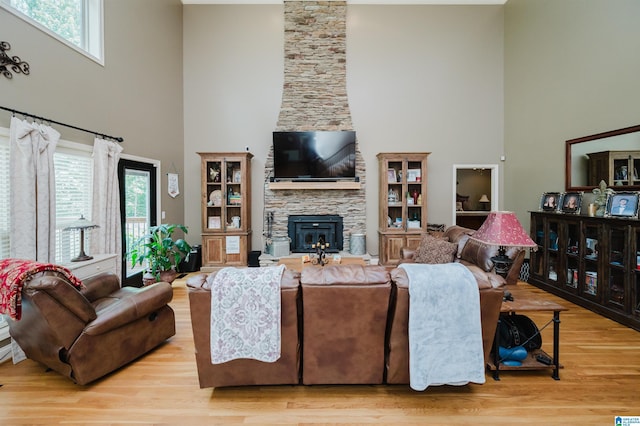 living room with a fireplace, light hardwood / wood-style flooring, and a high ceiling