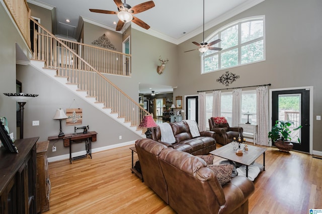 living room with crown molding, light hardwood / wood-style floors, ceiling fan, and a high ceiling