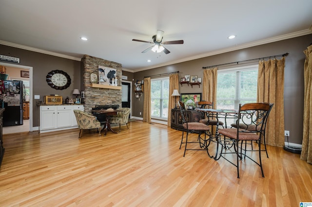 dining area with a stone fireplace, ornamental molding, light hardwood / wood-style floors, and ceiling fan