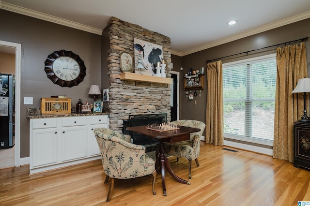 dining space featuring a fireplace, ornamental molding, and light wood-type flooring