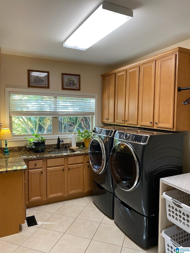 clothes washing area with sink, cabinets, light tile patterned floors, washing machine and dryer, and a healthy amount of sunlight