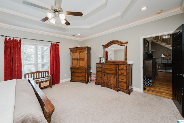 bedroom featuring ornamental molding, light carpet, ceiling fan, and a tray ceiling