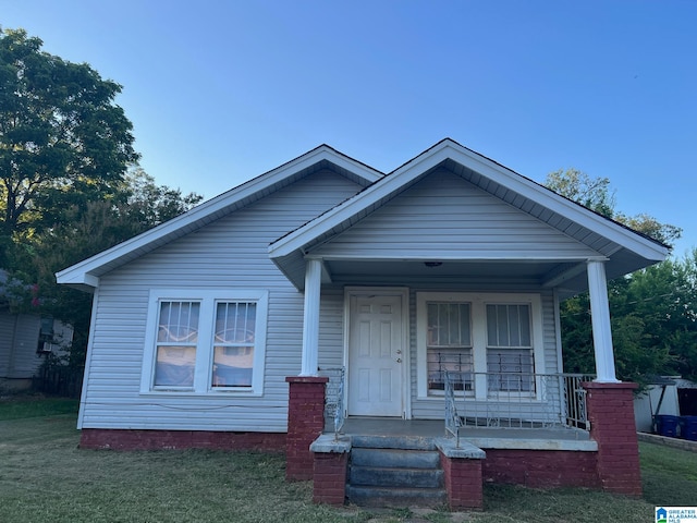 bungalow featuring covered porch and a front yard