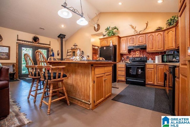 kitchen with black appliances, hanging light fixtures, vaulted ceiling, tasteful backsplash, and a kitchen bar