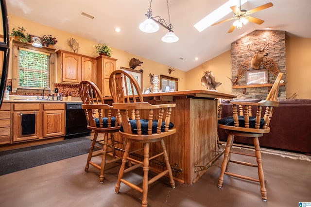 bar featuring backsplash, lofted ceiling with skylight, sink, decorative light fixtures, and dishwasher