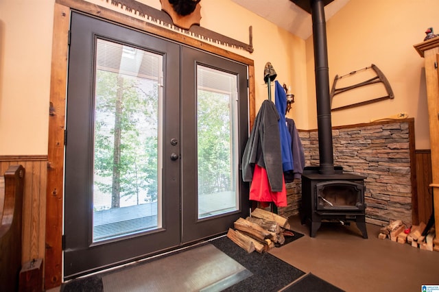 doorway to outside with a wood stove, wooden walls, and french doors