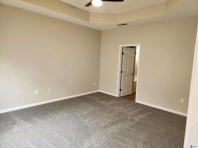 carpeted empty room featuring a tray ceiling and ceiling fan