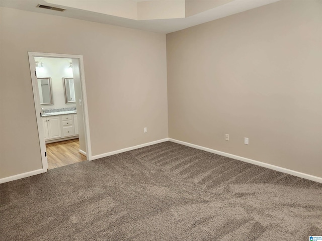 unfurnished bedroom with light carpet and ensuite bathroom