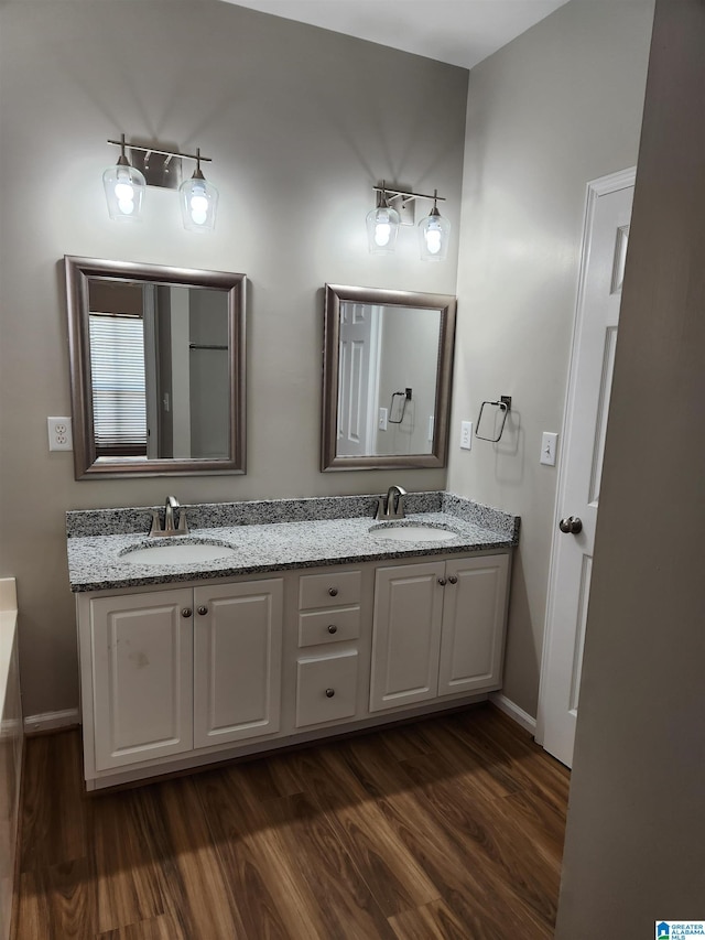 full bath featuring double vanity, baseboards, a sink, and wood finished floors