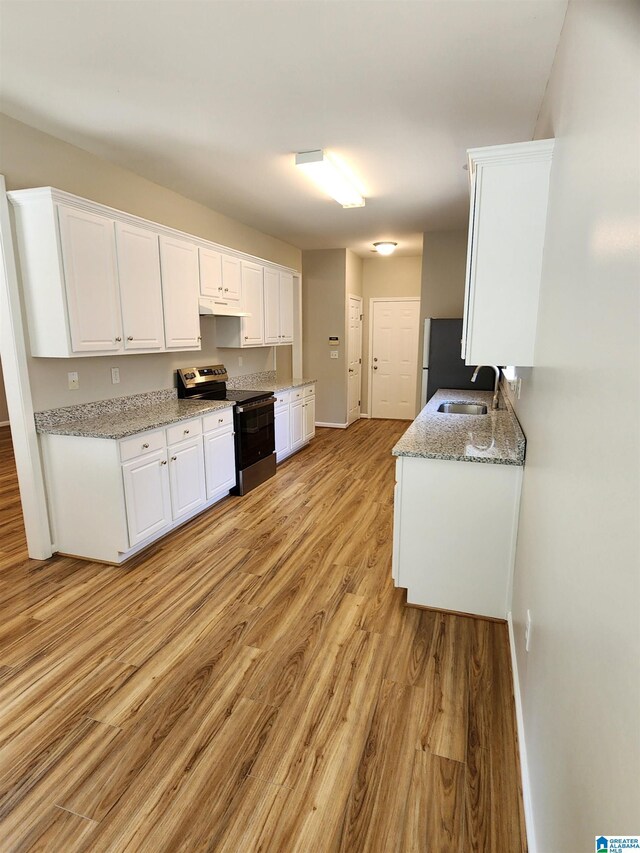 kitchen featuring stainless steel electric stove, sink, light hardwood / wood-style floors, and white cabinetry