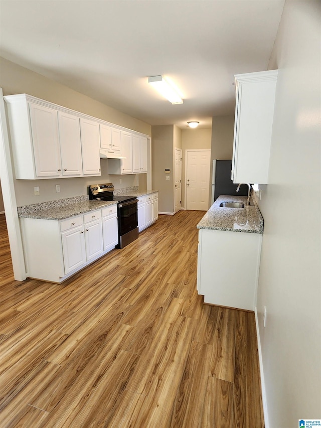 kitchen with light stone counters, a sink, white cabinetry, stainless steel electric range oven, and light wood finished floors