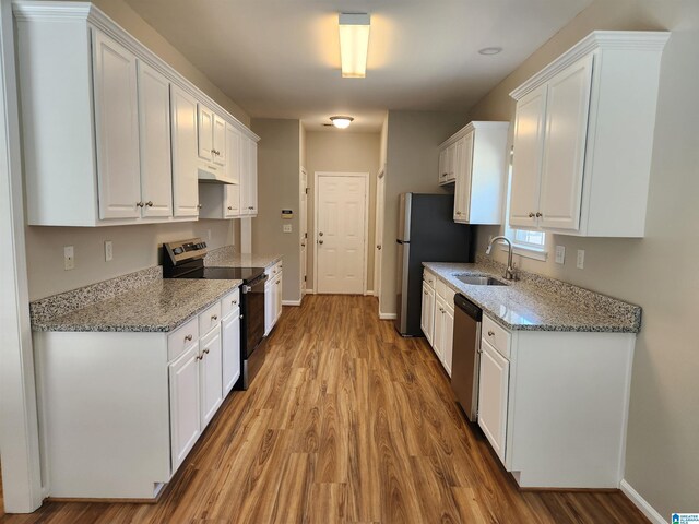 kitchen featuring light stone counters, sink, hardwood / wood-style flooring, white cabinetry, and appliances with stainless steel finishes