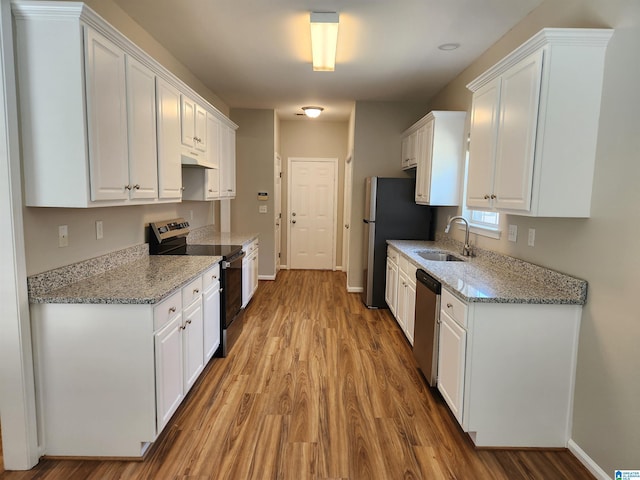 kitchen featuring appliances with stainless steel finishes, white cabinets, a sink, and light stone countertops