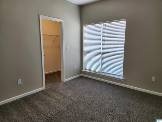 unfurnished room with dark colored carpet and baseboards