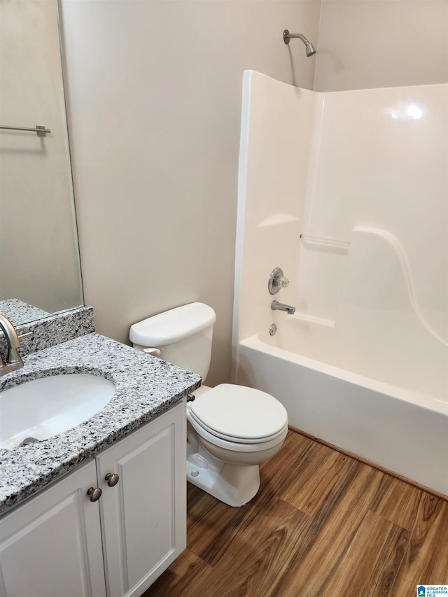 full bathroom with toilet, washtub / shower combination, wood finished floors, and vanity