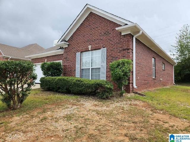 view of side of property featuring an attached garage, a yard, and brick siding