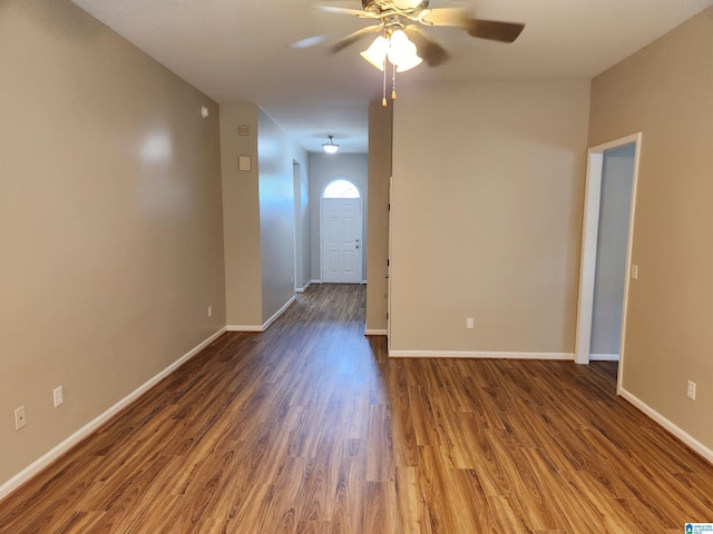 unfurnished room with dark wood-style floors, a ceiling fan, and baseboards