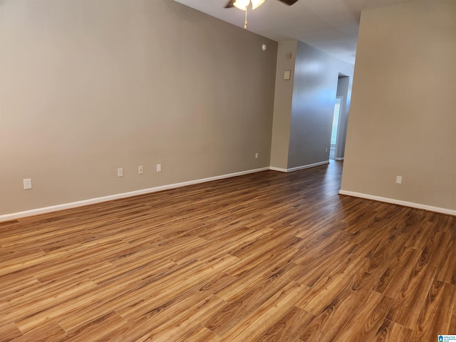 spare room featuring light wood finished floors, a ceiling fan, and baseboards