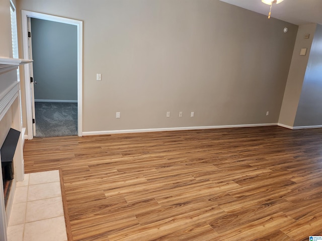 empty room with a tile fireplace and light wood-type flooring