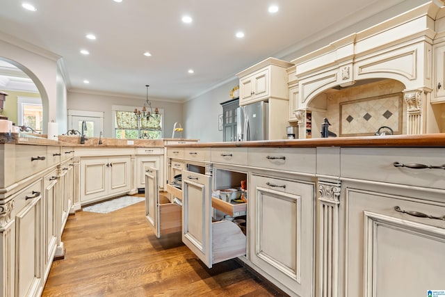 kitchen with cream cabinetry, a notable chandelier, decorative light fixtures, and wooden counters