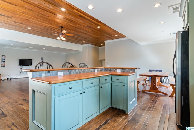 kitchen with dark wood-type flooring, stainless steel appliances, tasteful backsplash, green cabinets, and ornamental molding