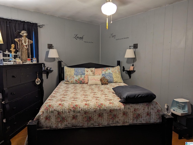 bedroom featuring hardwood / wood-style floors, ceiling fan, and wood walls