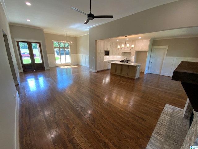 unfurnished living room with ceiling fan with notable chandelier, dark hardwood / wood-style flooring, crown molding, and sink