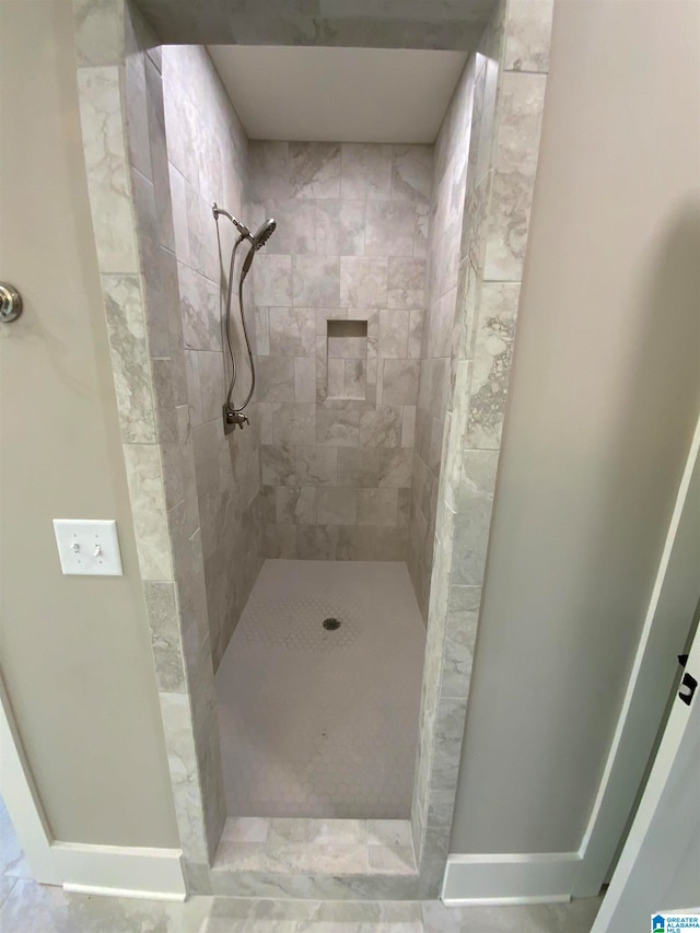 bathroom with tiled shower and tile flooring