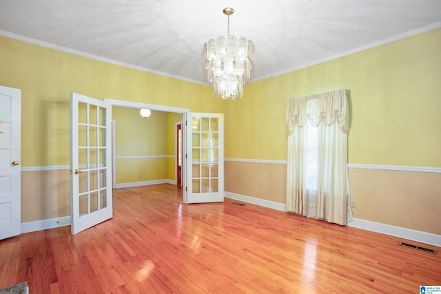 spare room with french doors, a chandelier, and ornamental molding