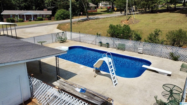 view of swimming pool with a patio, a diving board, a lawn, and a water slide