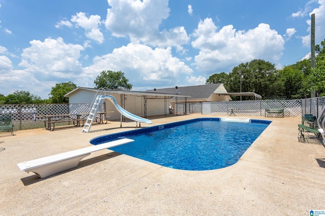 view of swimming pool with a patio area, a diving board, and a water slide