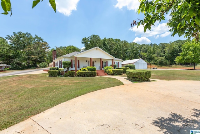 view of front of house with an outbuilding, a garage, a porch, and a front yard