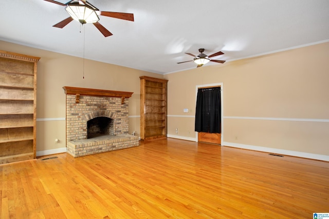 unfurnished living room with ceiling fan, a fireplace, light wood-type flooring, and ornamental molding