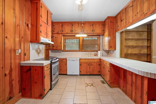 kitchen with stainless steel electric range oven, tile counters, backsplash, white dishwasher, and light tile patterned floors