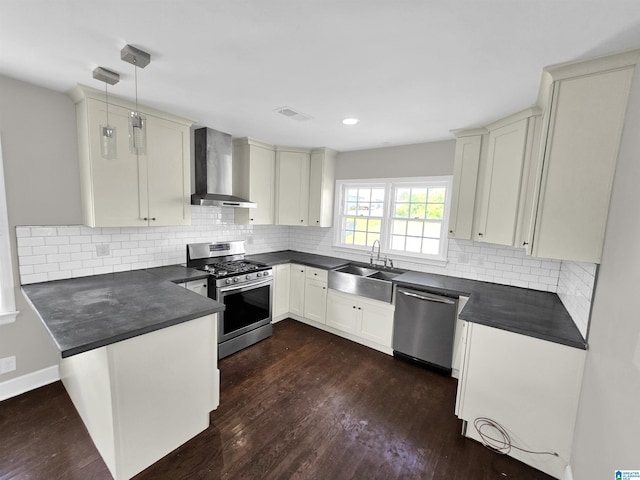 kitchen featuring stainless steel appliances, sink, wall chimney range hood, pendant lighting, and dark hardwood / wood-style floors