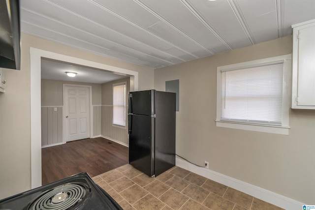 kitchen featuring black refrigerator and white cabinetry