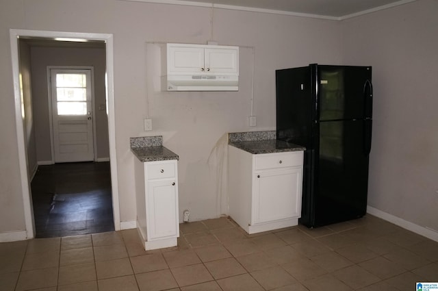 kitchen featuring ornamental molding, light tile patterned floors, black refrigerator, white cabinets, and dark stone countertops