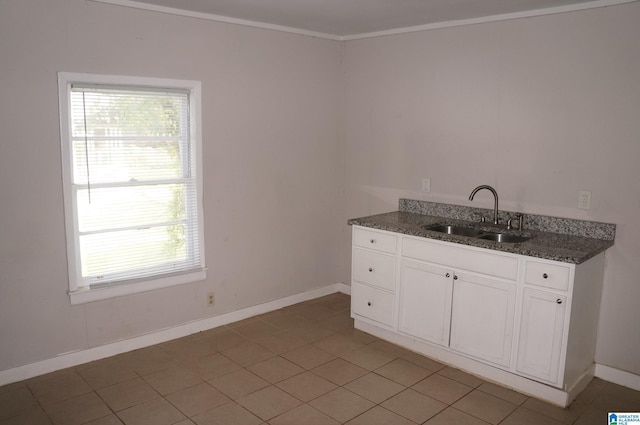 interior space with sink, white cabinetry, dark stone countertops, light tile patterned floors, and ornamental molding